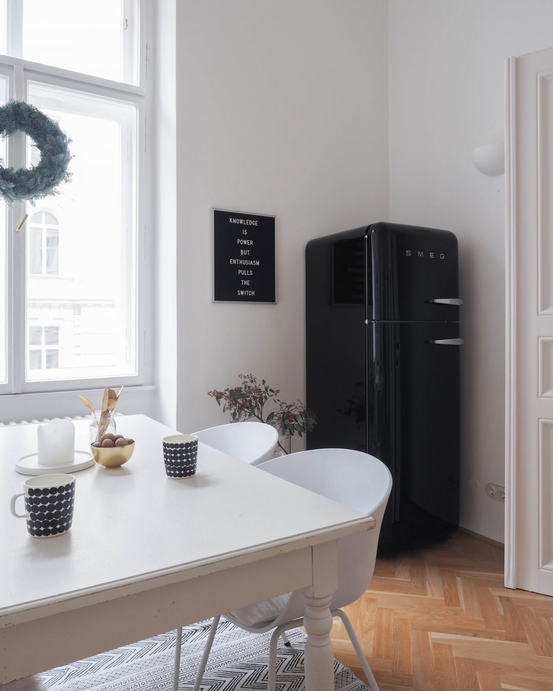 Eine küche mit einem schwarzen kühlschrank und einem tisch mit
